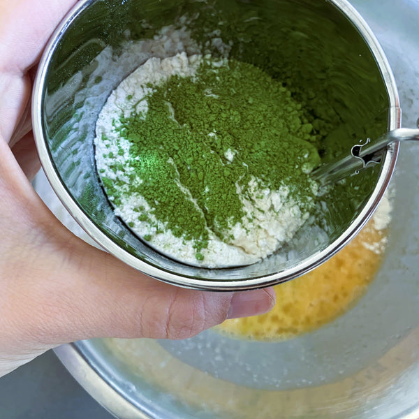 sifting the matcha powder and flour into the egg mixture