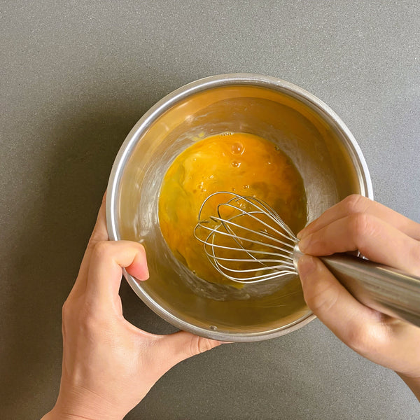 beating the eggs in a mixing bowl