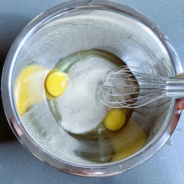 adding the eggs and sugar to the bowl and mixing
