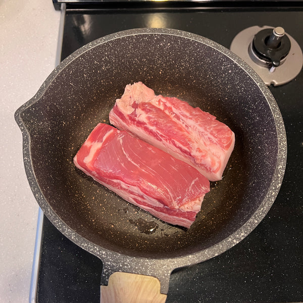adding the pork belly to a pot