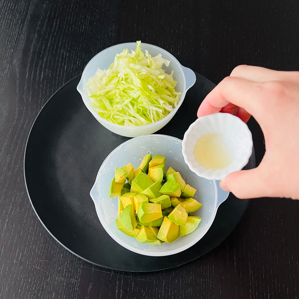 shredded lettuce and pouring lemon juice on top of the avocado