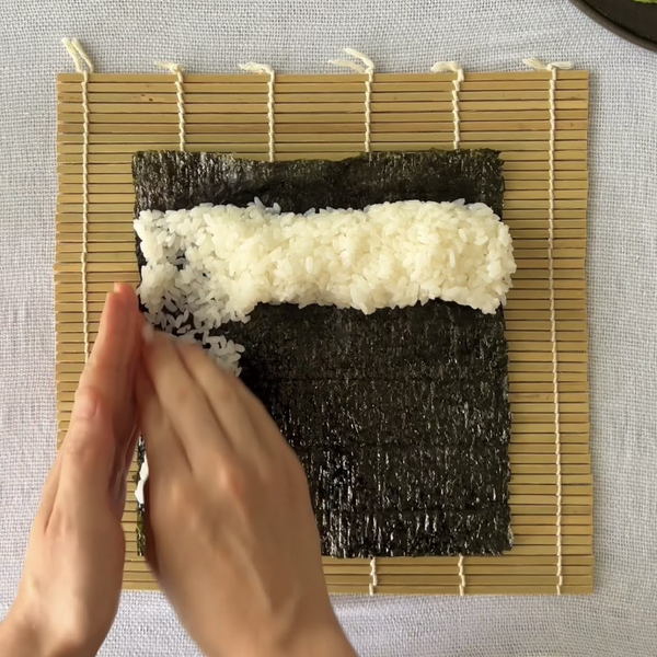 beginning to spread the sushi rice across the nori seaweed sheet