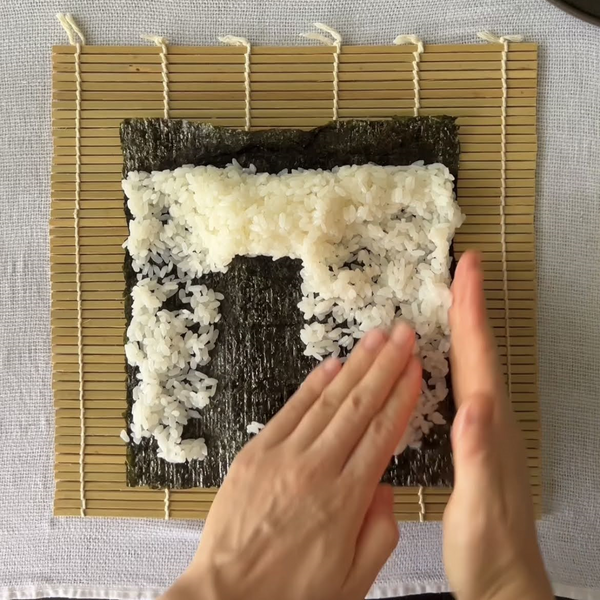 continuing to spread the rice across the nori seaweed sheet