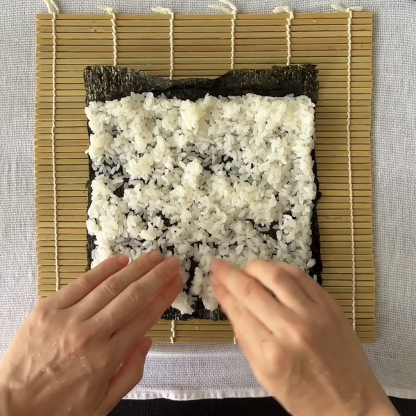 rice spread out evenly across the nori seaweed sheet