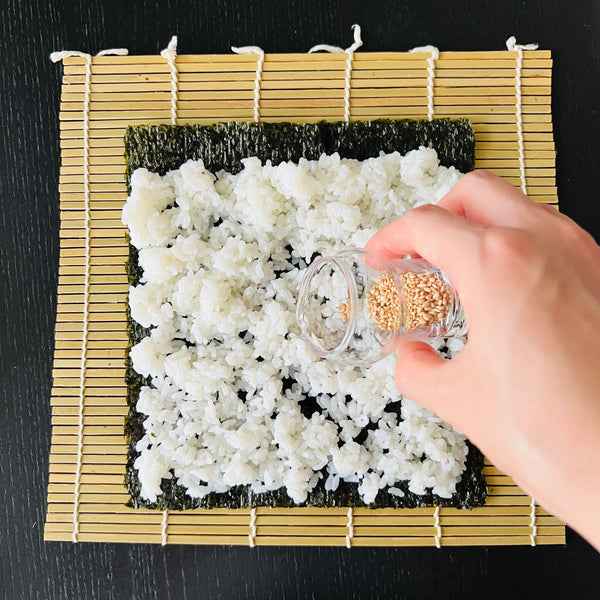 adding sesame seeds to the sushi rice