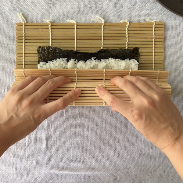 rolling the avocado roll with a bamboo rolling mat