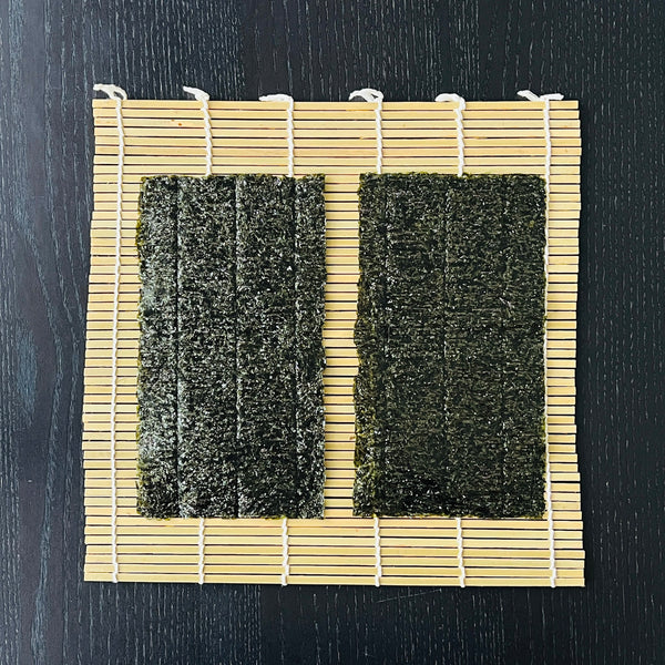 placing two pieces of nori seaweed onto a bamboo rolling mat