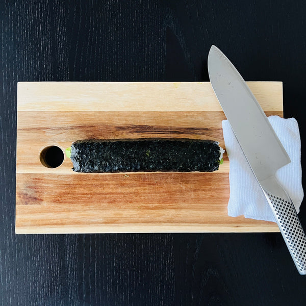 wetting a kitchen knife before cutting the avocado roll