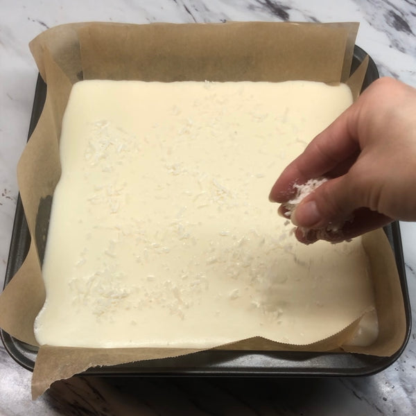 sprinkling coconut flakes on top of the butter mochi