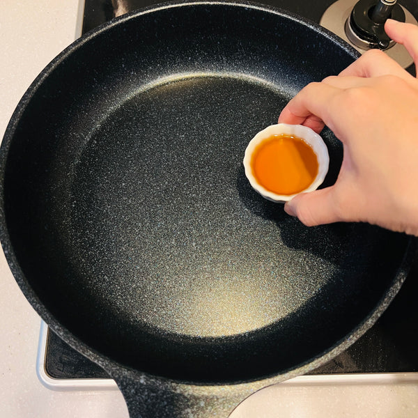 adding sesame oil to a frying pan