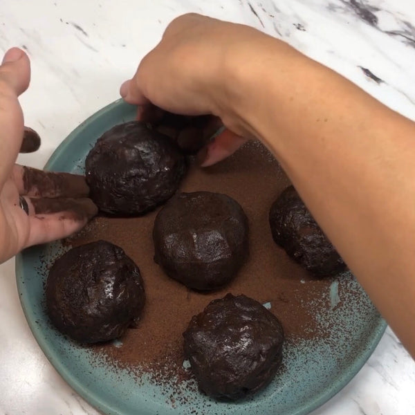 dusting each piece of chocolate mochi with more cocoa powder