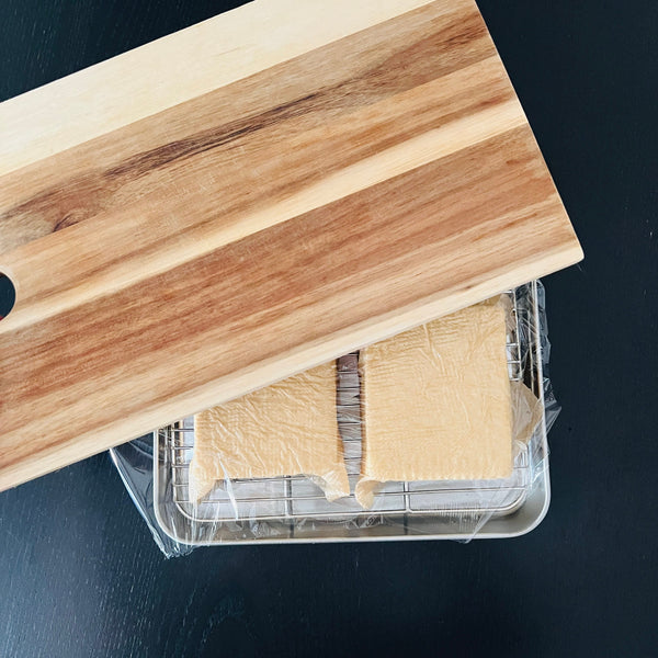 placing a cutting board over the tofu