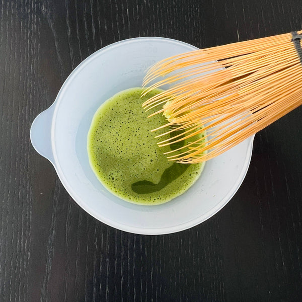 whisking the matcha with a bamboo whisk