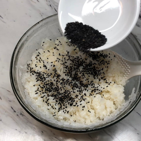 adding black sesame seeds to the sushi rice