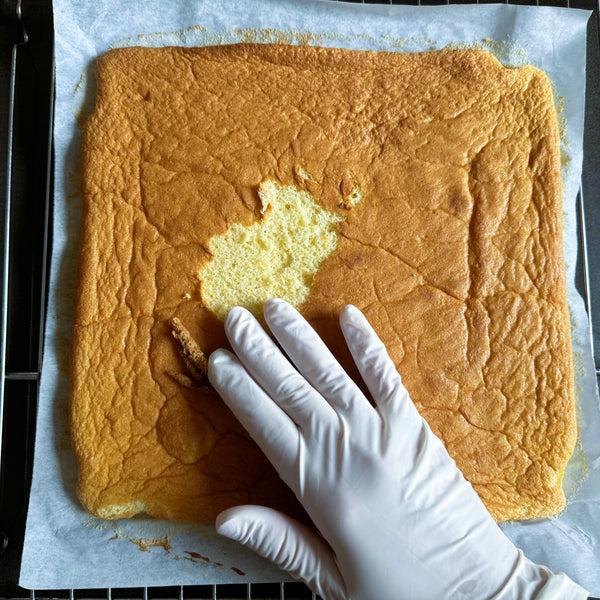 removing the cake from the parchment paper lined baking tray and adding it to a silicone mat