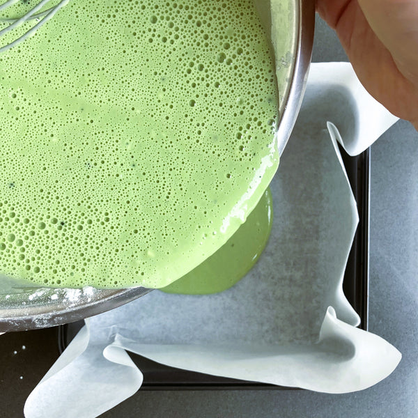 pouring matcha batter into the prepared baking pan
