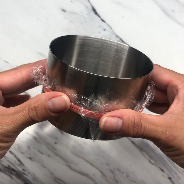 lining a mold with a piece of plastic wrap and rubber band