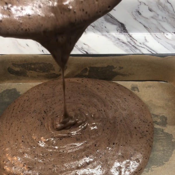 pouring the chocolate sponge cake batter into a baking sheet