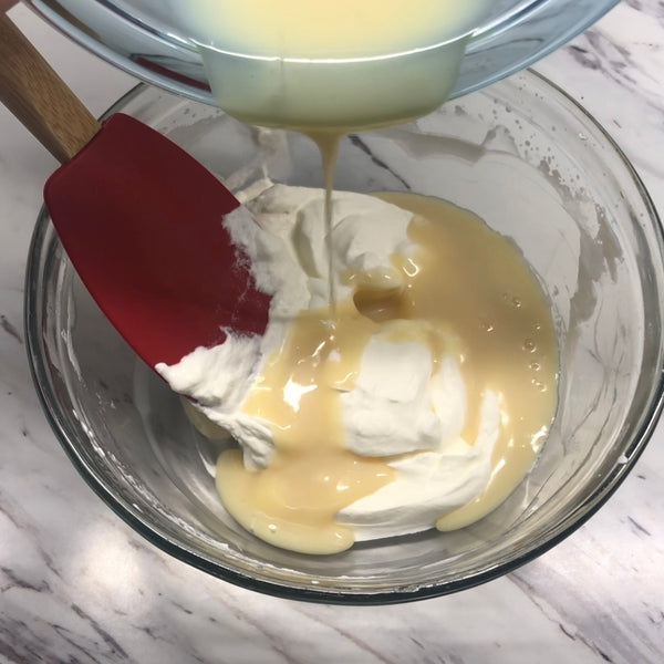 adding the white chocolate mixture to the whipped cream