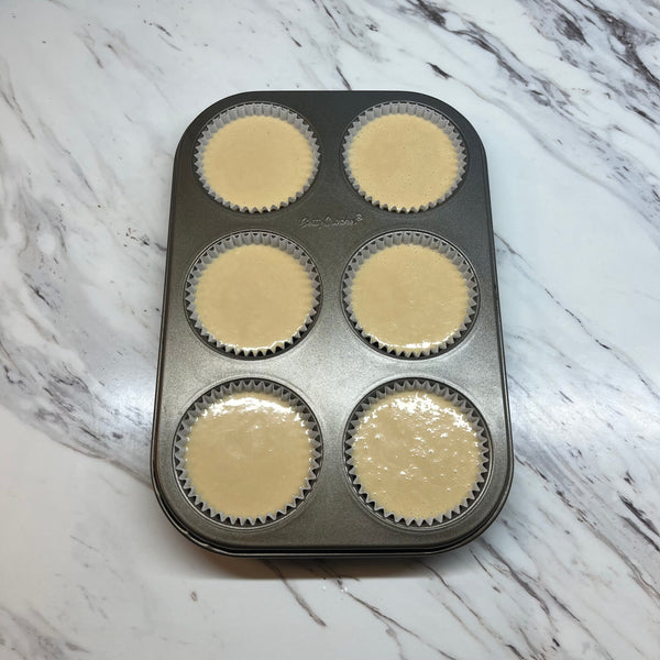 pouring the mochi muffin batter into the lined muffin cups