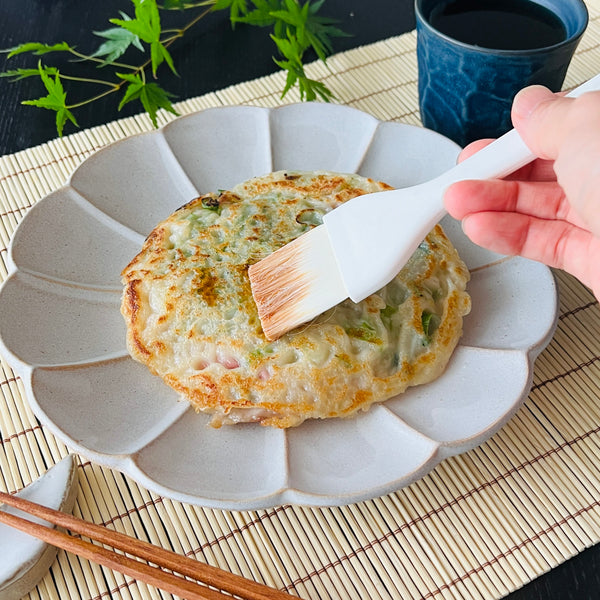 brushing soy sauce over negiyaki