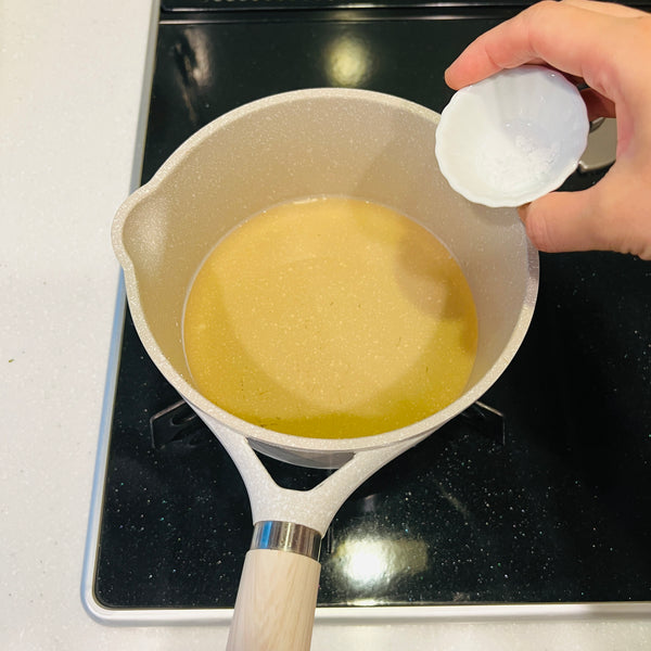 heating the dashi and seasoning it with a pinch of salt