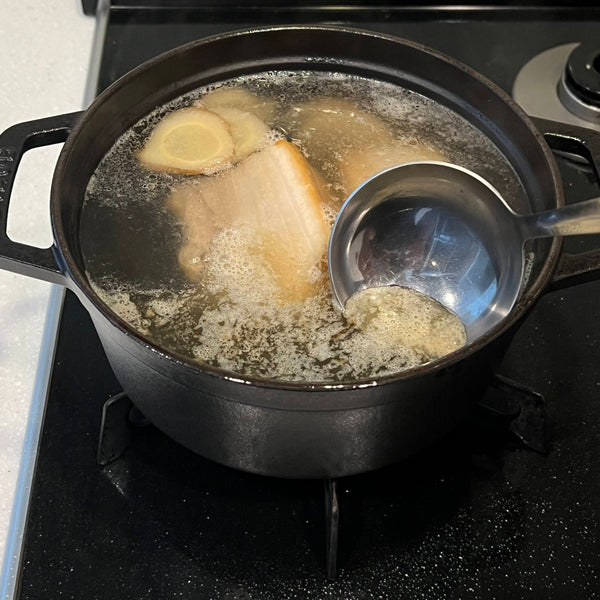 simmering the pork belly and removing excess scum that floats to the surface