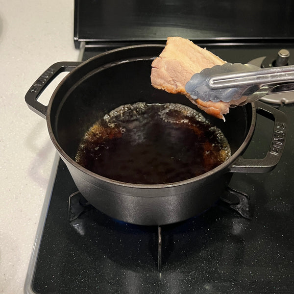 adding the pork belly slices to the braising liquid