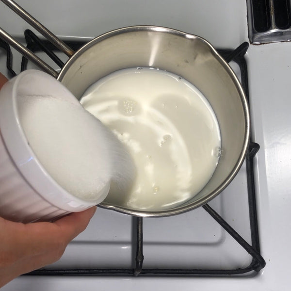 adding the sugar and milk to a pot