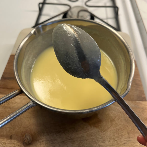 checking the custard's thickness by drawing a line on the back of a spoon