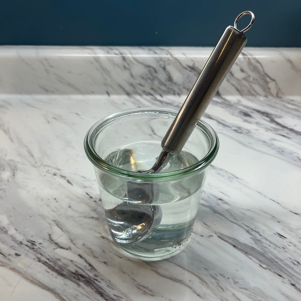 placing an ice cream scoop in a cup of warm water