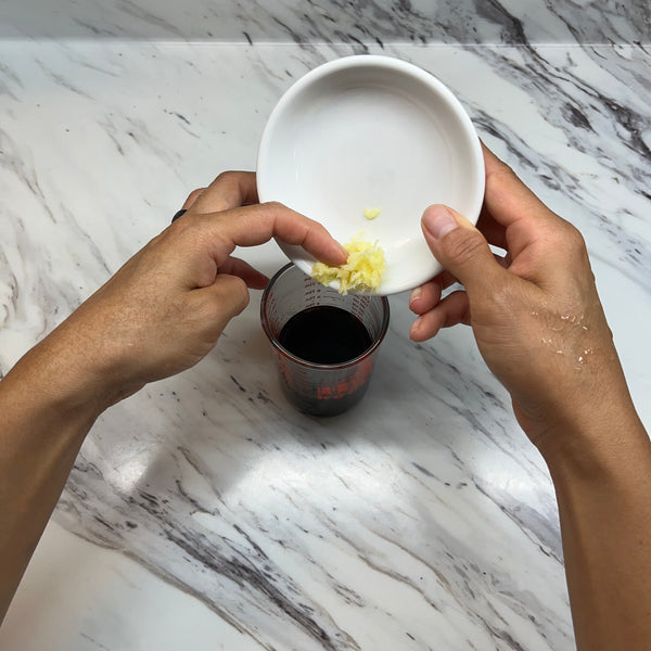 pouring the grated ginger into the dressing