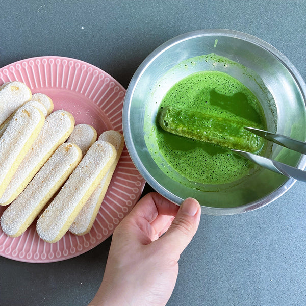 dipping the other side of the ladyfinger into the matcha