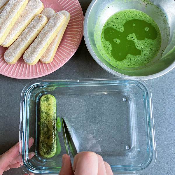 laying the matcha-soaked ladyfinger into the container