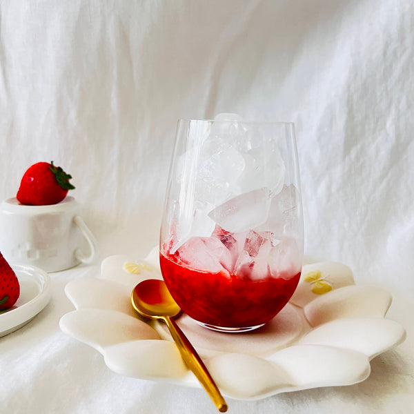adding crushed strawberries and ice to a glass