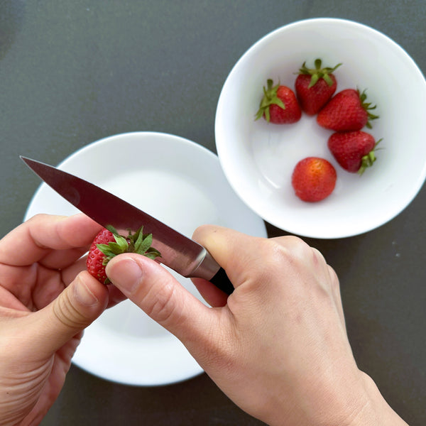 slicing the stems off of the strawberries