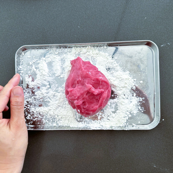 adding the mochi dough to a tray dusted in potato starch