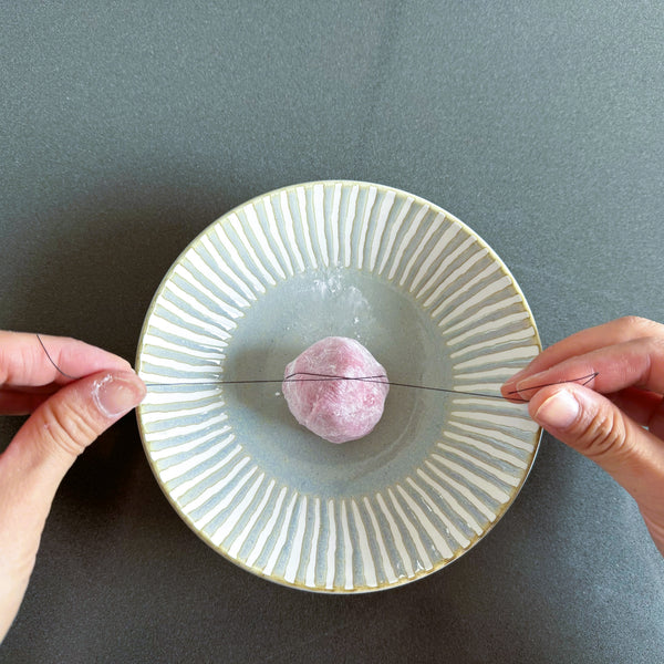 using a string to cut strawberry mochi in half