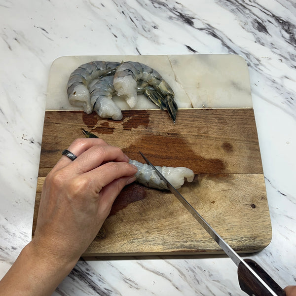 using a knife to make slits into the shrimp