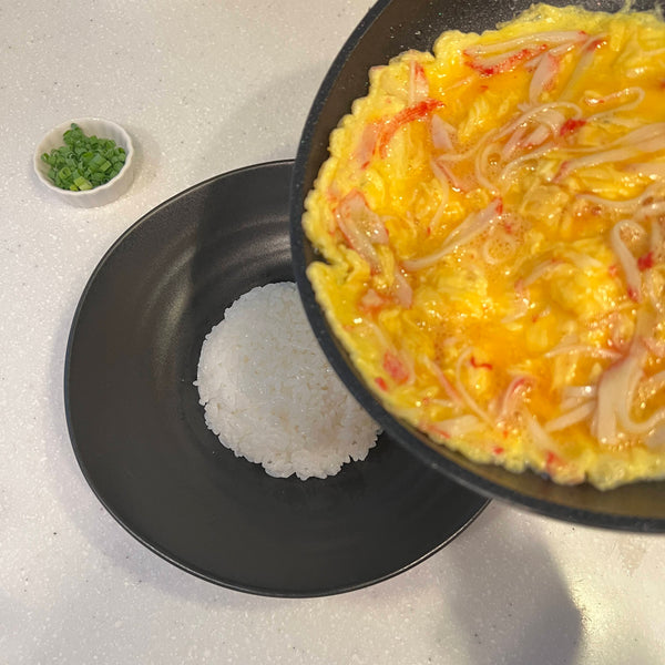 pouring the crab omelet over the rice