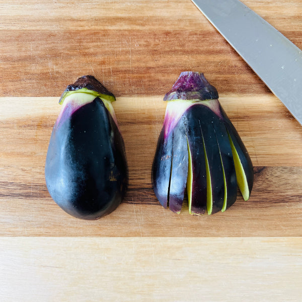 cutting the eggplant in half and making cuts on the surface to fan out the eggplant