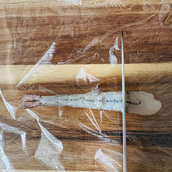 flattening the shrimp with the back of a knife