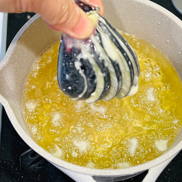 dipping the prepared eggplant tempura into the hot oil