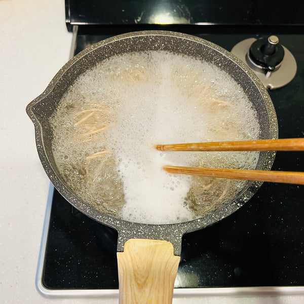 stirring the soba noodles in boiling water