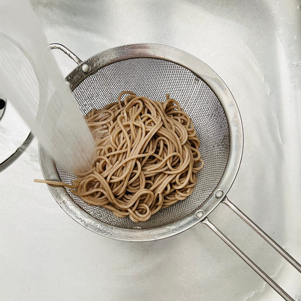 draining the soba noodles and then running them under cold water to cool them down