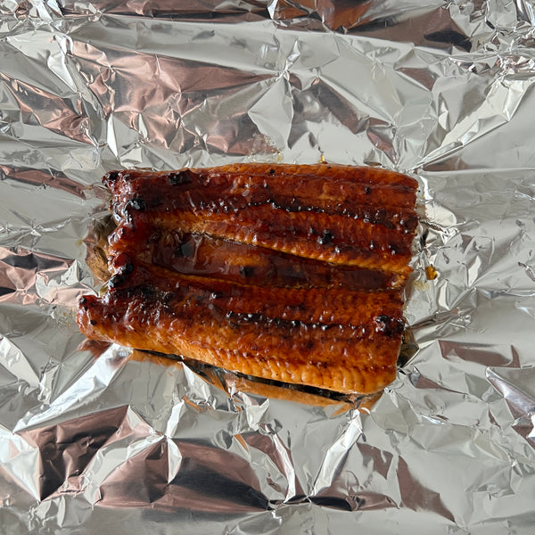 placing a piece of unagi inside of a piece of foil