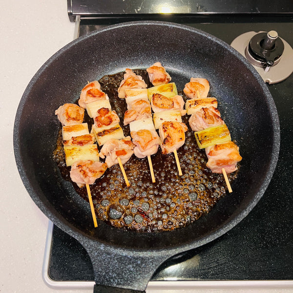 adding the yakitori back to the pan with the tare
