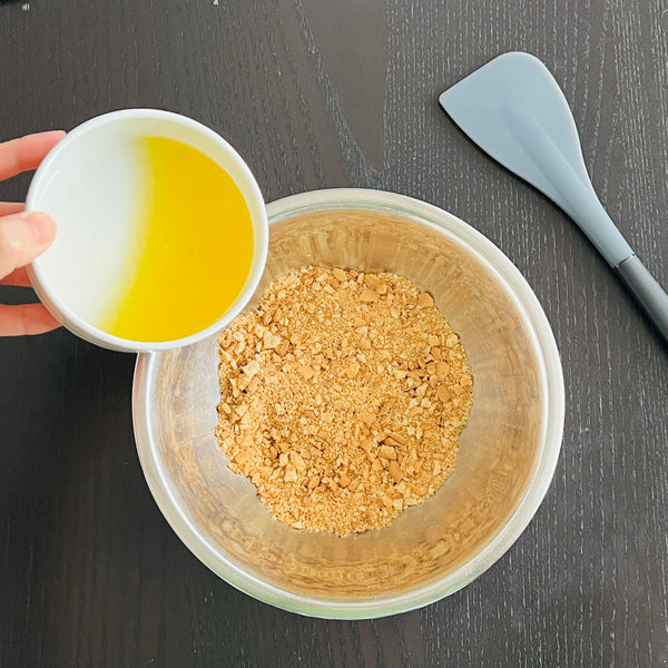 adding melted butter to the crushed biscuits