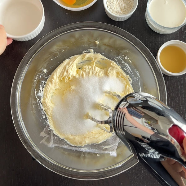 adding the sugar to the whipped cream cheese