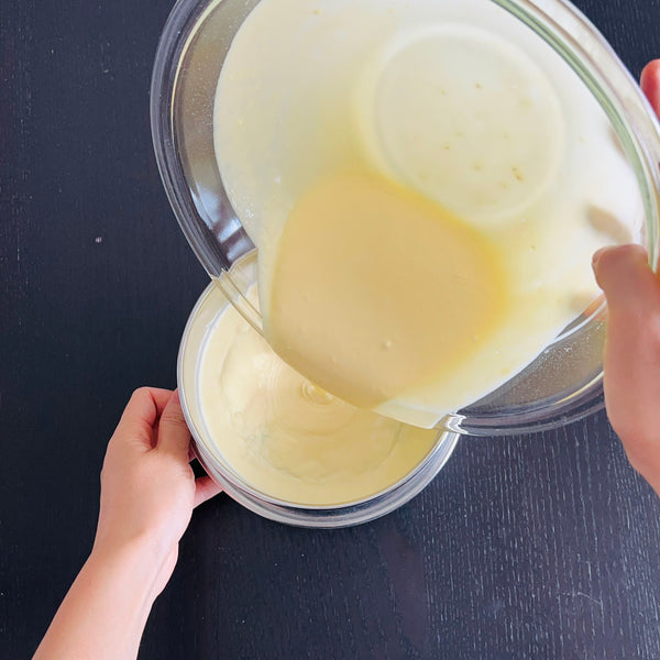 pouring the yuzu cheesecake batter into a sieve to smooth it out